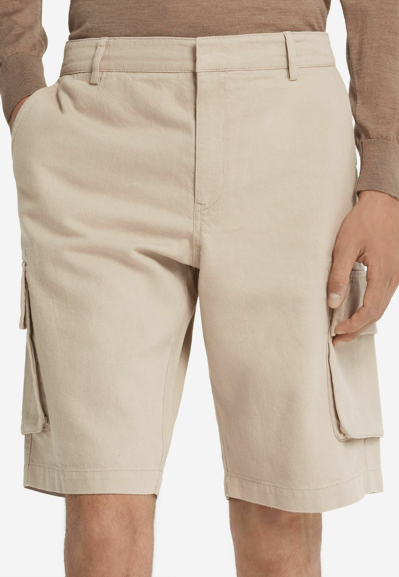 Beige Cargo-Shorts aus strapazierfähigem Material, mit zwei Seitentaschen und zwei großen Cargotaschen auf jeder Seite. Flacher Schnitt.