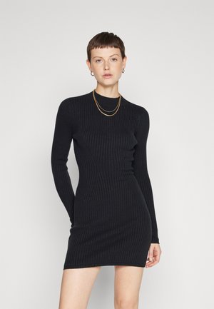 Black ribbed long-sleeve dress with a fitted design, round neckline, and textured fabric. It falls above mid-thigh, showcasing a sleek silhouette.