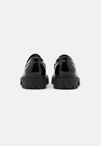Scarpe in pelle verniciata nera con suola spessa nera e punta arrotondata, caratterizzate da una finitura liscia e dettagli di cucitura minimi.