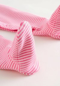 Rosa randiga strumpor med mjuk textur, med spetsig tådesign och kontrasterande vita ränder, arrangerade mot en ljus bakgrund.