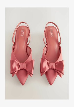 Chaussures à talons rose satinées avec un bout pointu et un grand nœud sur le devant. Texture lisse et design à talon ouvert.