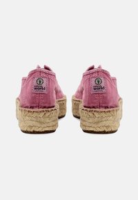 Roze platnene espadrile s pletenom jutenom petom, koje imaju malu zelenu oznaku s strane i šivane detalje na gornjem dijelu.