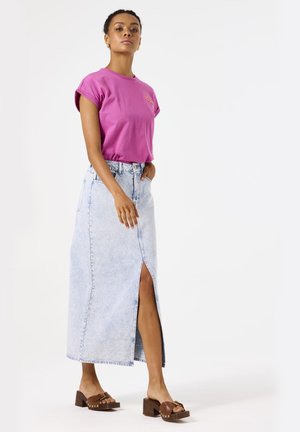 Pink short-sleeve t-shirt paired with a light blue denim maxi skirt featuring a front slit and brown heeled sandals with gold accents.