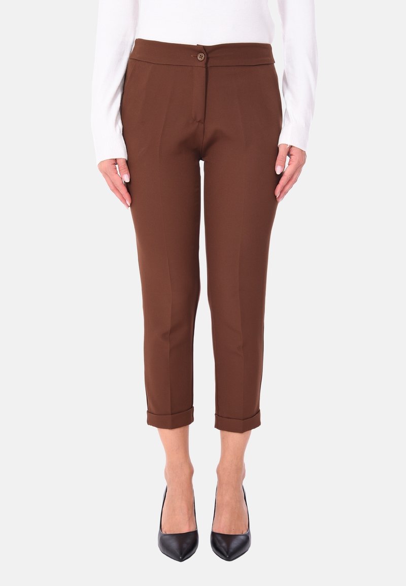 Pantaloni marroni su misura realizzati in tessuto liscio, con chiusura a bottone, lunghezza alla caviglia e orli arrotolati. Indossati con tacchi neri.