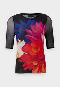 Korte mouwen t-shirt met een zwarte netoverlay en een kleurrijk bloemenpatroon in rood, roze en blauw tegen een donkere achtergrond.