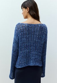 Maglione lavorato a maglia in diverse sfumature di blu, caratterizzato da un design all'uncinetto allentato, scollo ampio e maniche lunghe con orli a coste.