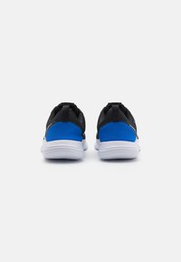 Baskets de sport noires et bleues avec une tige lisse et texturée, un talon rembourré et une semelle en caoutchouc blanche. Comprend deux languettes pour un enfilage facile.