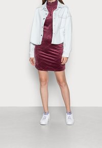 Denim jacket, light blue, cropped design; burgundy velvet dress, slim fit with textured pattern; white sneakers with purple accents.