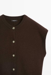 Brązowy sweter z dzianiny z krótkim rękawem, z okrągłym dekoltem i złotymi guzikami z przodu. Gładka tekstura z delikatnym żebrowaniem.