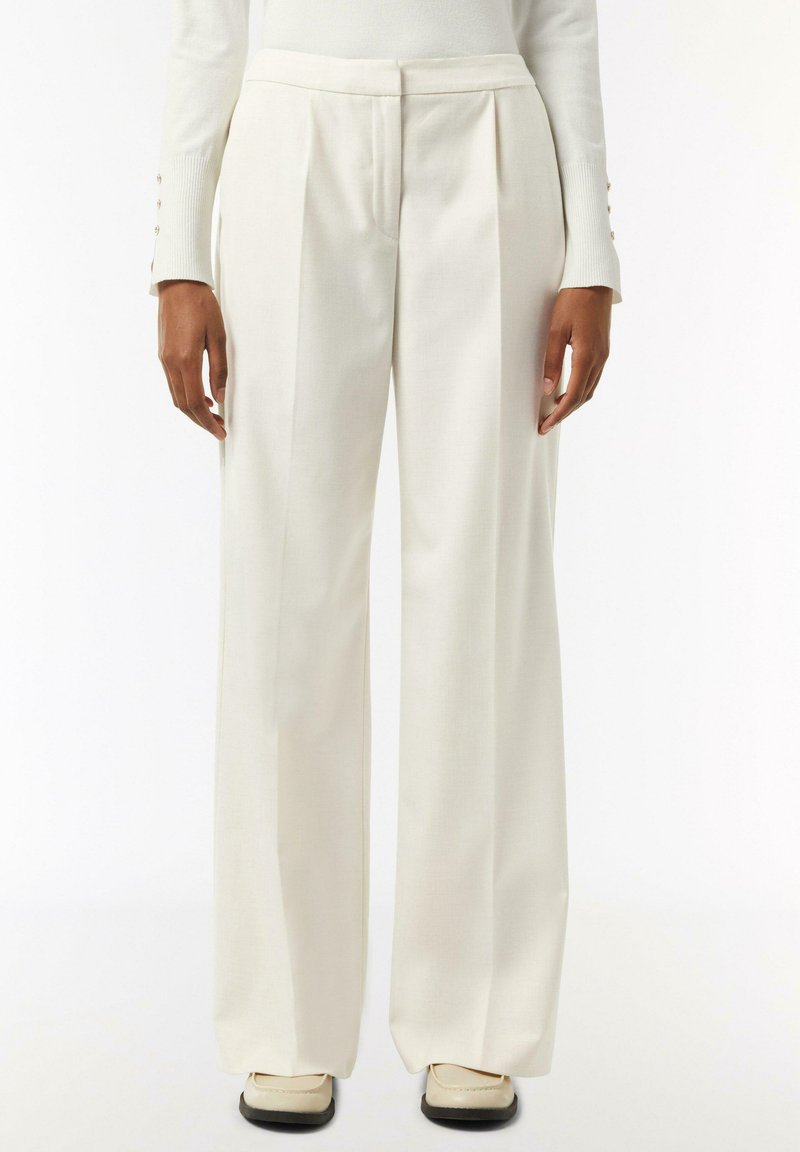 White, pleated trousers with a relaxed fit, featuring a smooth texture and subtle stitching details, paired with light-colored shoes.