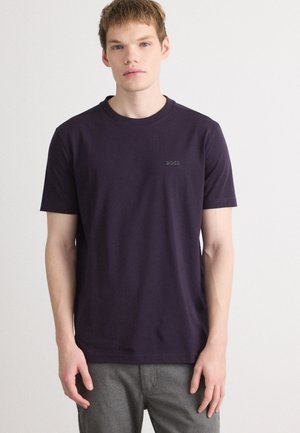 Tricou cu guler rotund de culoare mov, fabricat din bumbac, cu un logo subtil pe pieptul stâng și mâneci scurte. Textură netedă, croială casual.