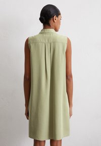 Robe à manches courtes, longueur genou en vert clair, dotée d'un col, d'un pli dans le dos et d'une texture de tissu lisse et respirante.