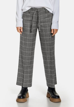 Harmaat, leveälahkeiset ruudulliset housut, joissa edessä solmittava vyö, yhdistetty mustiin paksupohjaisiin saappaisiin ja valkoiseen pitkähihaiseen puseroon.