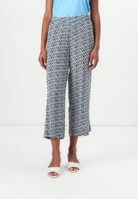 Pantaloni cropped a fantasia in bianco e navy, caratterizzati da un design geometrico, cintura elastica e orlo svasato, abbinati a sandali con punta aperta.