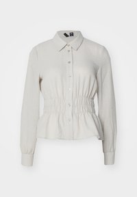 Camicia color beige chiaro con colletto, maniche lunghe, arricciatura elastica in vita e chiusura con bottoni sul davanti. Tessuto testurizzato e traspirante.