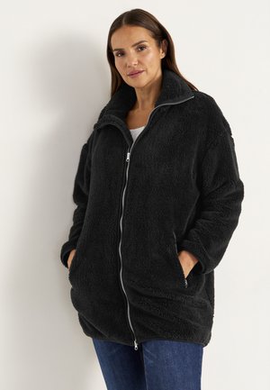 Schwarze Fleece-Jacke mit hohem Kragen, durchgehendem Reißverschluss und seitlichen Taschen. Strukturierter, weicher Stoff; lockere Passform, die bis zur Mitte des Oberschenkels reicht.
