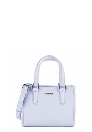 Bolso pequeño de cuero color púrpura claro con herrajes plateados, doble asa superior, correa ajustable para el hombro y logo "LACOSTE" en la parte frontal.