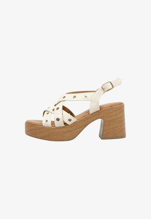 Sandale plateforme en cuir beige avec talon bloc en bois, brides croisées avec œillets métalliques et boucle réglable à la cheville.