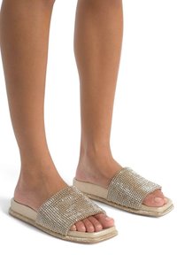 Beige slipper sandalen met een plat ontwerp, versierd met sprankelende rhinestones en een gladde textuur aan de bovenkant.