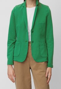 Zelený sako s klopovým límcem, dvěma předními kapsami a knoflíkovým zapínáním. Obsahuje jednoduché prošívání a hladkou texturu.