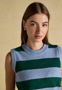 Mėlynos ir tamsiai žalios dryžuotos be rankovių megztinis, su raštuotu apvaliu kaklu ir minkšta, tekstūruota apdaila.