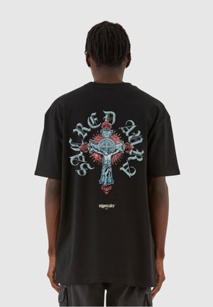 Sort bomulds t-shirt med et stort farverigt grafisk motiv af et kors og udsmykket tekst på ryggen, med røde og blå accenter.