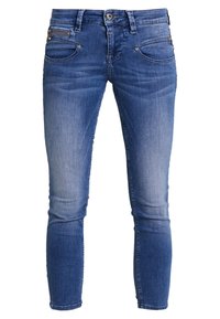 Jeans ajustados en denim azul medio con un ligero desgastado, cinco bolsillos, un bolsillo con cremallera y detalles en metal plateado.