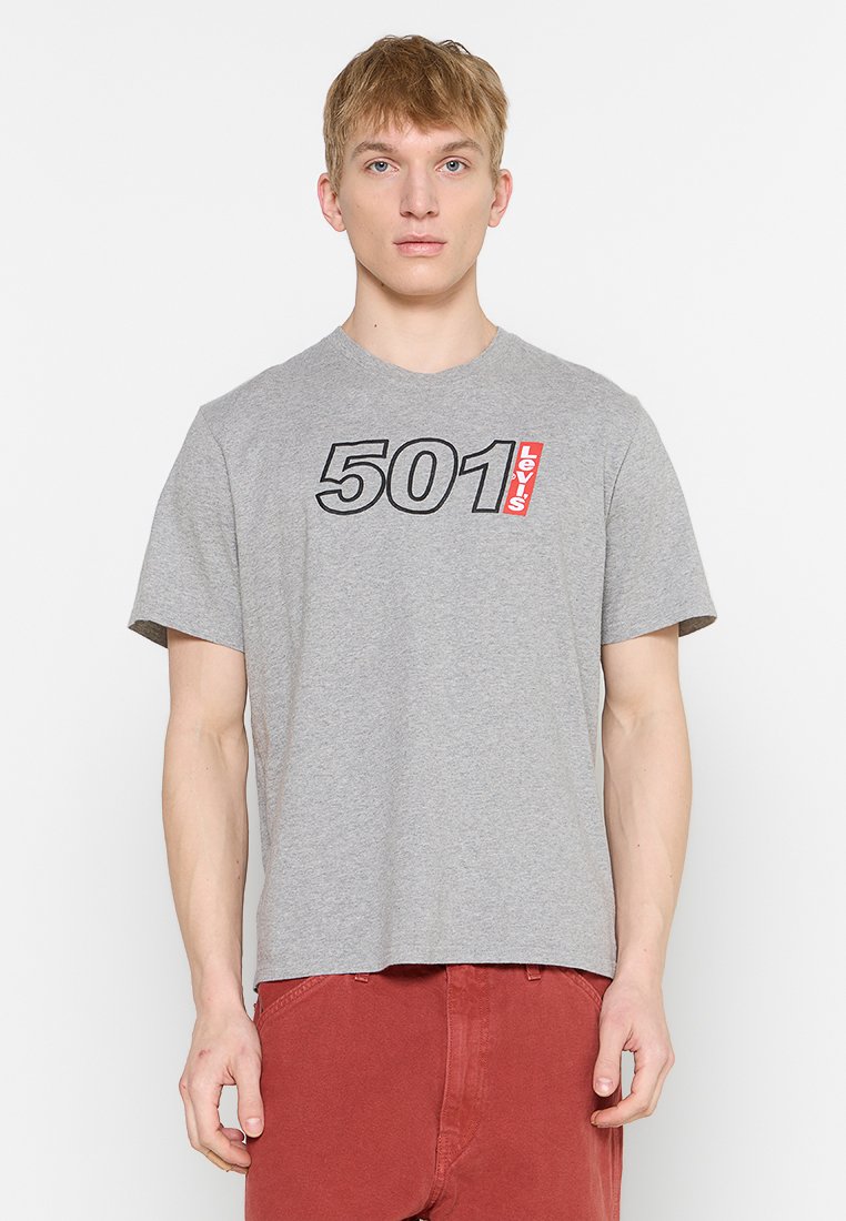 T-shirt en coton gris avec un grand graphisme "501" et le logo "Levi's" en rouge. Manches courtes, col rond, coupe décontractée. Design épuré.