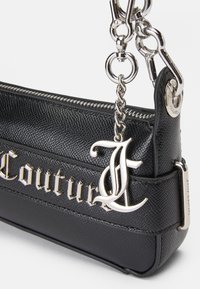 Bolsa de mão preta em pele com superfície texturizada, ferragens prateadas e um detalhe de logotipo em metal. Apresenta fecho em zip e um suporte de corrente.