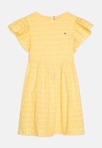 Żółta bawełniana sukienka z krótkimi, falbaniastymi rękawami, posiadająca plisowaną spódnicę oraz subtelne teksturowane paski. Małe logo na piersi.