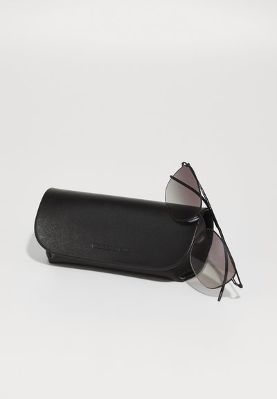 Black aviator sunglasses with gradient lenses resting on a textured black case, featuring embossed branding. Smooth surfaces and sleek design.