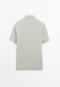 Polo a maniche corte in tessuto grigio chiaro, con colletto classico e un design pulito e semplice senza pattern o dettagli visibili.