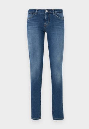Blå, smale jeans i denim med frontknapp, glidelås og femlommersdesign mot en ensfarget lys bakgrunn.