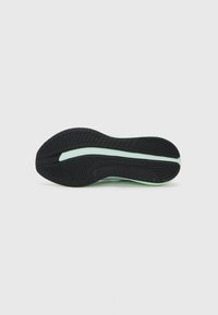 Suela de zapatilla negra de goma con un patrón texturizado; acento en verde menta claro que recorre el centro. Acabado liso con secciones de agarre elevadas.