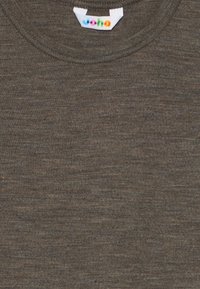 T-shirt en tricot marron à col ras du cou avec une petite étiquette blanche au col portant les lettres colorées "woha".