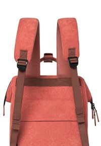 Zaino in velluto a coste color corallo con spallacci imbottiti e regolabili, maniglia superiore e dettagli in webbing marrone. Presenta un compartimento con zip e una texture a coste verticali.