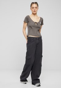 Grå cropped topp med kort erm, med detaljer i nøkkelhull. Mørke baggy cargo bukser med sidelommer og slitte sømmer.