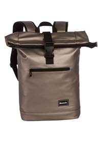 Sac à dos gris à rabat avec une finition brillante et imperméable. Il dispose d'accents noirs, d'une poche zippée à l'avant et de bretelles réglables.