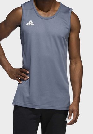 Grå sports tanktop med struktureret stof, rund halsudskæring og Adidas-logo på brystet. Lang model, parret med sorte bukser.