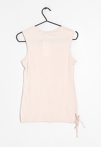 Top senza maniche rosa chiaro realizzato in tessuto morbido, con scollatura rotonda e un dettaglio a cravatta in basso a sinistra. Logo Puma sul retro.