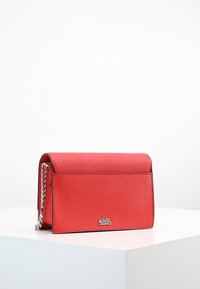 Borsa a tracolla rossa in pelle con finitura testurizzata, tracolla in catena argentata e chiusura a patta magnetica. Logo sul fondo anteriore.