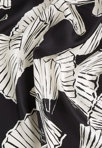 Svart stoff med hvitt grafisk blomsterdesign. Mønsteret har abstrakte former og fine linjer som fremhever tekstur og kontrast.