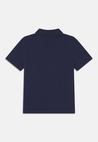 Námořnická modrá polo tričko s klasickým límečkem, krátkými rukávy a hladkou, texturovanou tkaninou. Žádné viditelné logo nebo vzory.