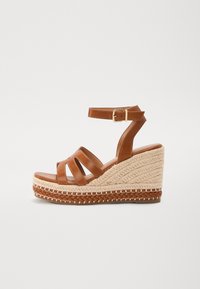 Bruine leren wedge sandalen hebben een gevlochten jute zool, een open teen ontwerp met drie banden en een gespsluiting rond de enkel voor een veilige pasvorm.