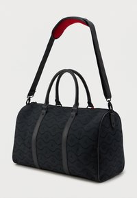 Fekete sporttáska dombornyomott logókkal, két rövid fogantyúval és állítható vállpánttal, amelynek belseje piros párnázott.
