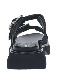 Sandalo nero con più cinturini e decorazioni in gioielli, soletta imbottita e una suola piatta spessa e texturizzata per stabilità.