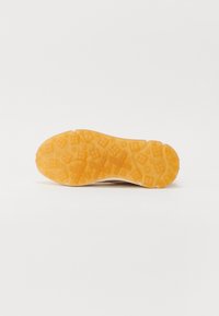 Sole of a sneaker, featuring a textured, orange rubber material with geometric patterns and a white midsole design.