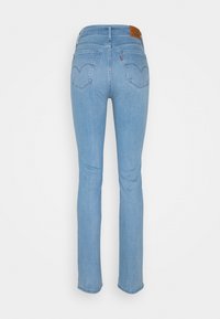 Jeans de denim azul claro con un diseño de pierna recta, que presentan un parche de cuero en la cintura, bolsillos traseros y detalles de costura mínimos.