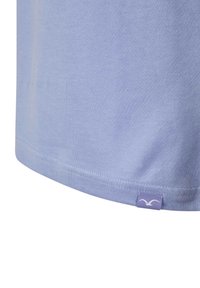 Hellblau-lila Baumwoll-T-Shirt mit abgerundetem Saum, minimalistischen Nähten und einem kleinen Markenetikett in der unteren linken Ecke.