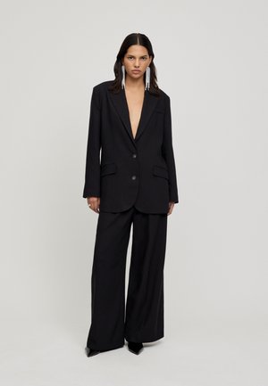 Black tailored blazer with a deep V-neck and two buttons, paired with wide-leg black trousers. Smooth fabric with minimal detailing.